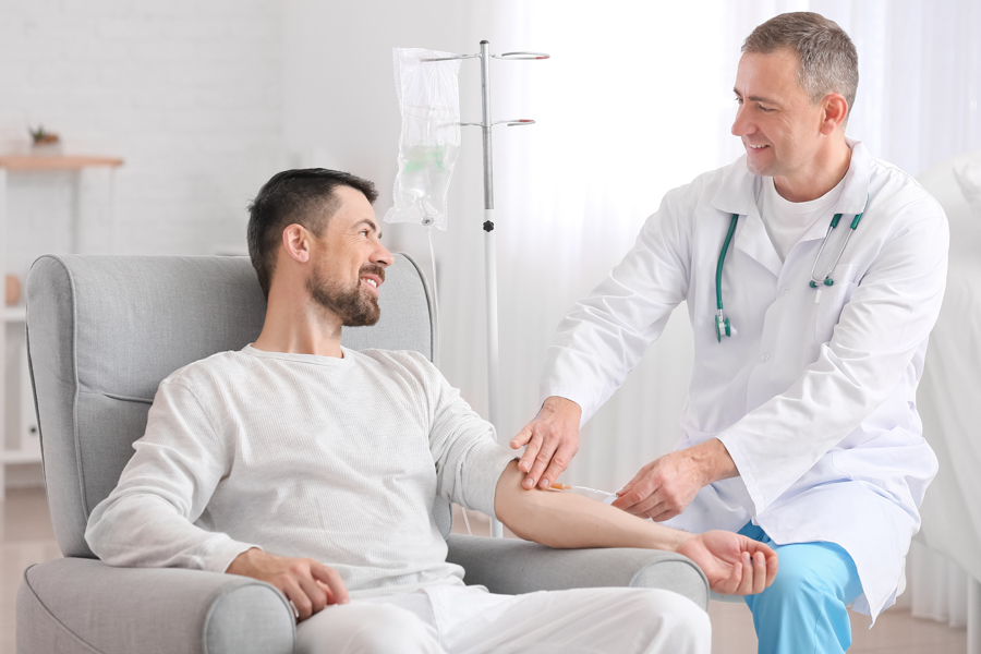 Doctor and man undergoing course of chemotherapy in clinic. Pros